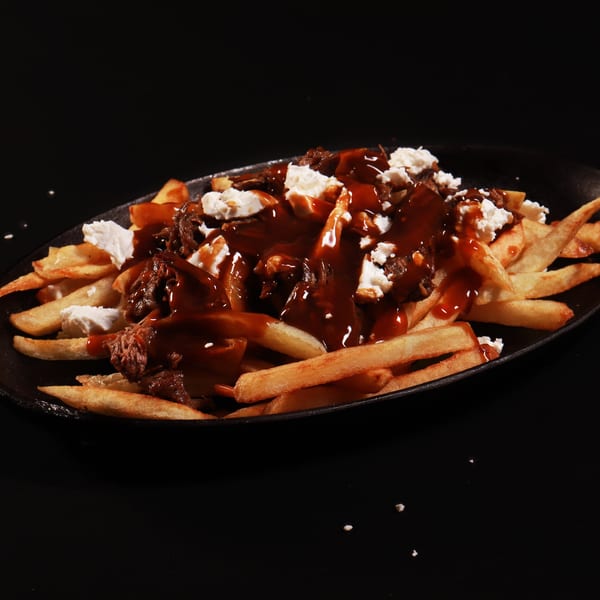 Close-up of poutine with crispy fries, rich gravy, pulled beef, and cheese curds.